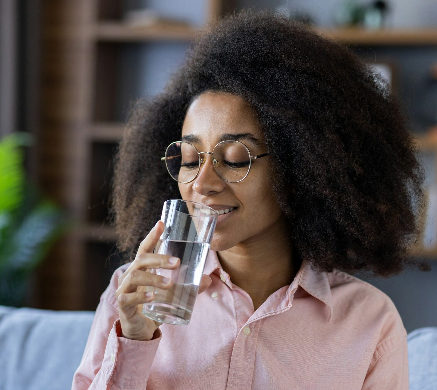 Young woman enjoying a refreshing glass of water at home