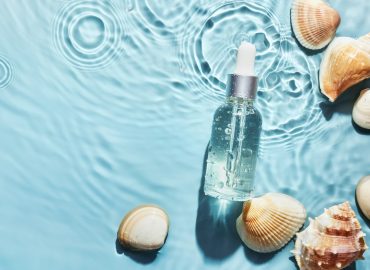 Organic cosmetic with sea minerals. Skincare cosmetic product and shells on blue water background